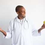 smiling-black-male-doctor-holding-green-red-apples_1262-12500